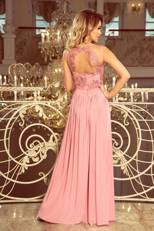 Woman in elegant pink gown at luxurious event.