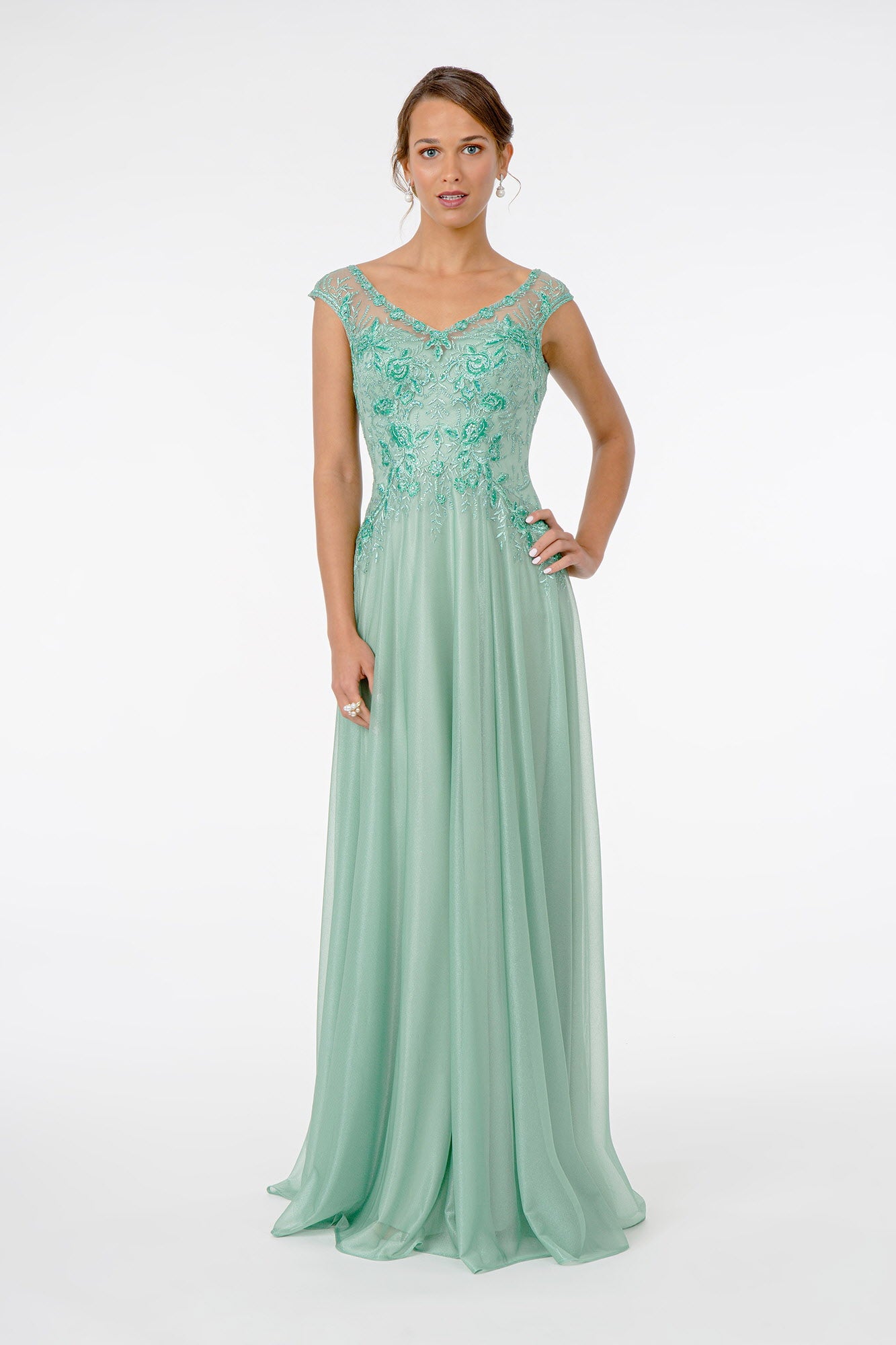 Woman in elegant green embroidered gown.
